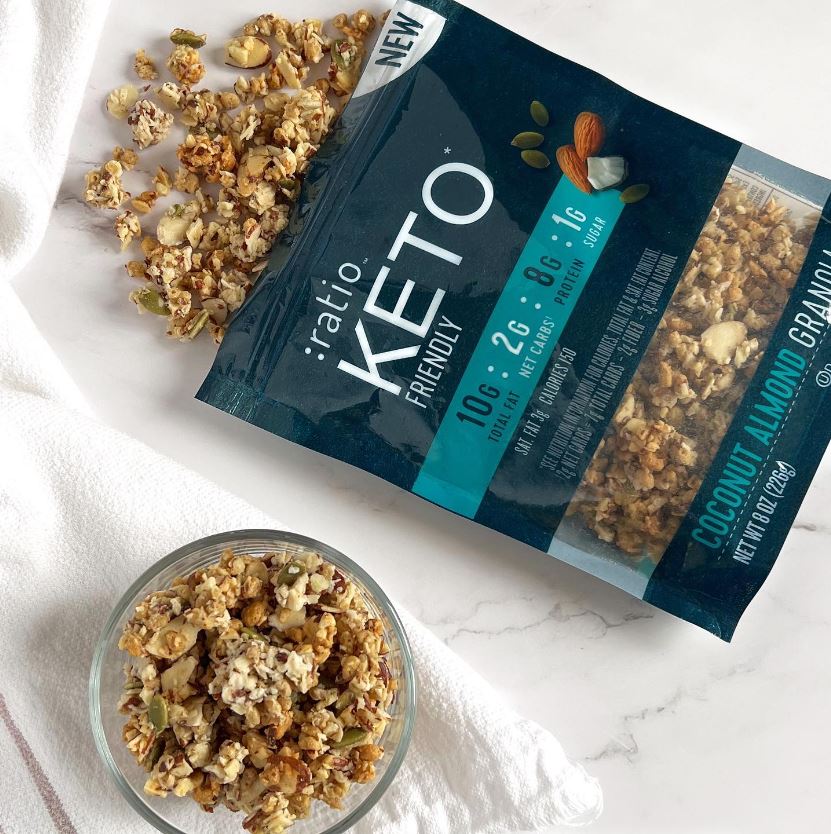 An open bag of Ratio KETO Friendly Granola with granola spilling out of the bag.