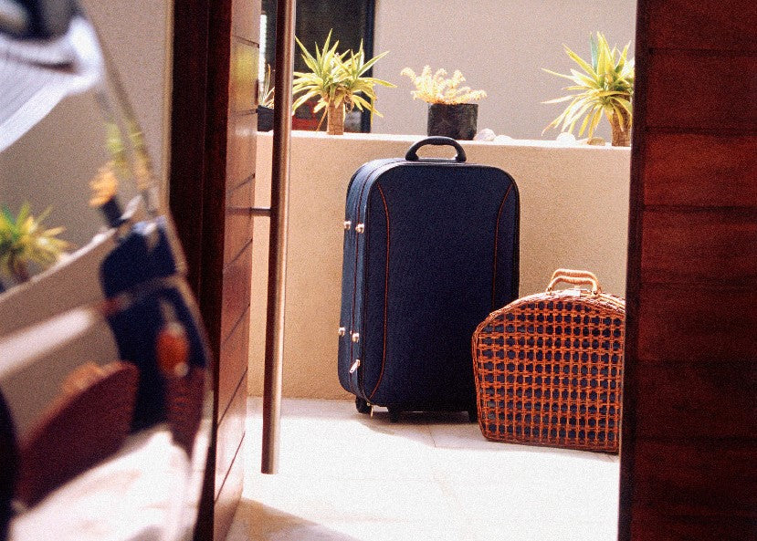 Open door to a balcony where two pieces of luggage are left against an outdoor wall.